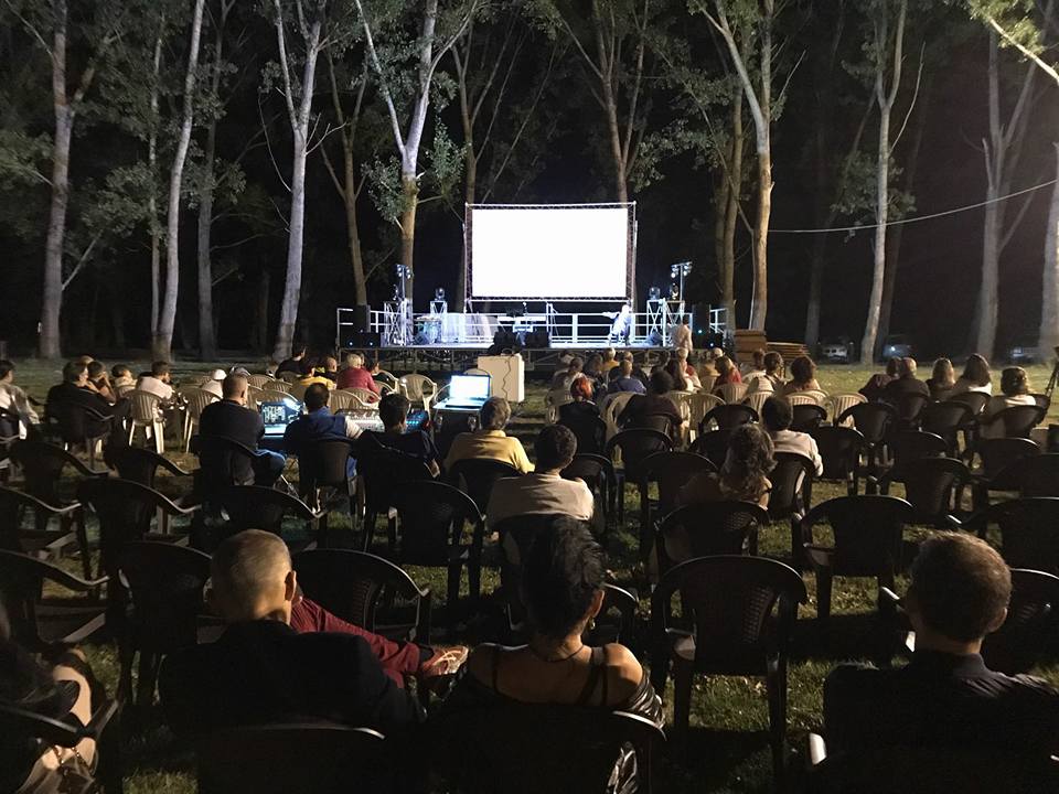 Gruppo di persone guardano un film all'aperto la sera