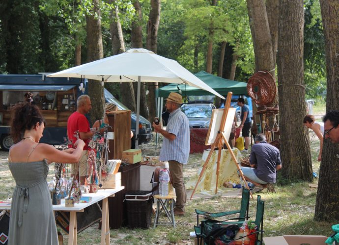 Persone in un mercato all'aperto, dove ci sono quadri e prodotti artigianali