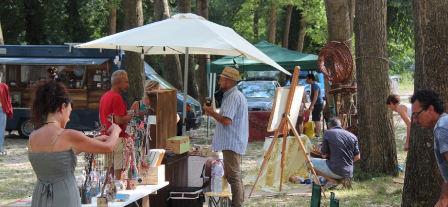 Persone in un mercato all'aperto, dove ci sono quadri e prodotti artigianali